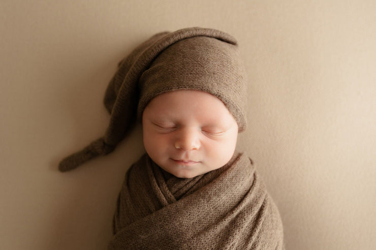 brown stretch fuzzy swaddling wrap and hat on newborn boy
