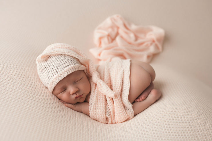 newborn girl with butt up in the air with peach sleepy hat for spring and summer photos