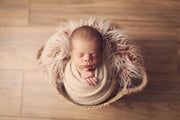 newborn baby swaddled in tan photography prop