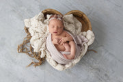 newborn baby girl in natural stained wooden bowl with legs and cream accent blankets
