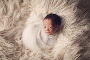 white newborn baby swaddled in fuzzy wrap with cream faux fur by custom photo props