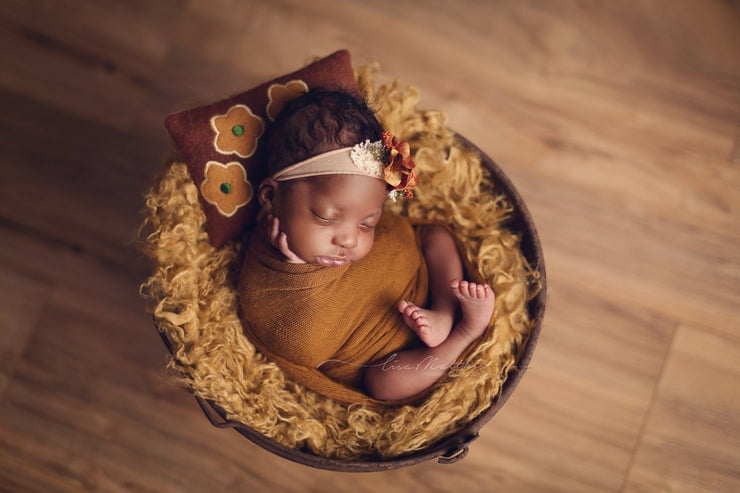 black newborn baby with mustard yellow curly faux fur, embroidered pillow and swaddling wrap for baby's first photos. props by custom photo props