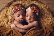 two newborn black girl twins with yellow fur, orange flower headband holding each other. newborn props by custom photo props