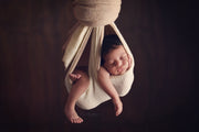 cream and beige newborn baby hanging in swaddling hammock photography prop