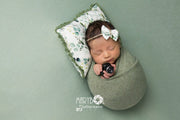 newborn girl on green posing cloth with mini camera and pillow
