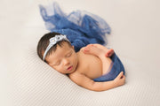 newborn girl swaddled in silk layering fabric with matching blue headband