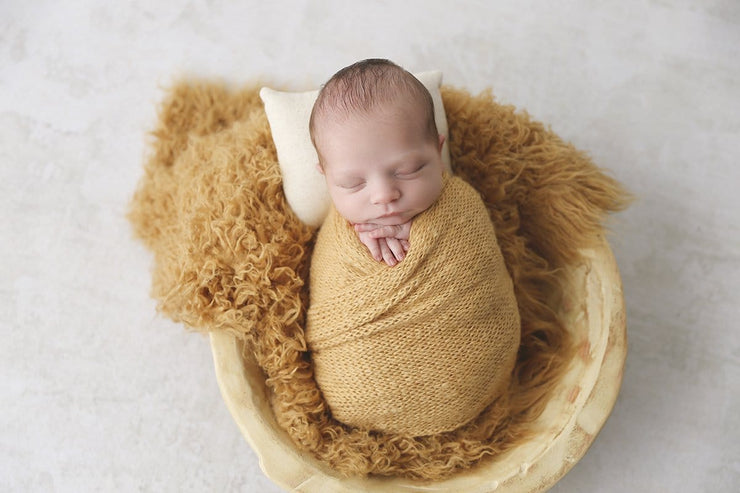 mustard yellow faux flokati newborn fur photography prop with boy swaddled in yellow wrap