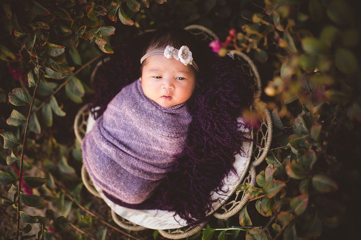 darker skin newborn baby with purple stretch swaddling wrap photo prop