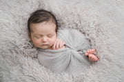 baby on light gray fur and wrapped in a gray mohair wrap