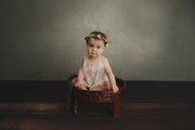 little girl sitting up for pictures with green backdrop and fake wood floor in mat