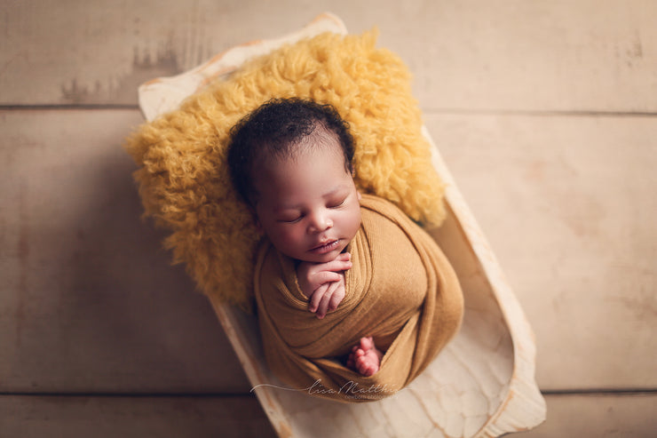 newborn african american baby boy with yellow fur and swaddling wrap photo prop for first photos 