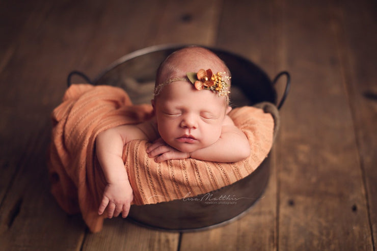 orange striped newborn baby girl on bucket with posing cloth and orange flower headband photography prop