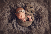newborn baby girl with light brown striped swaddle wrap, taupe headband and crochet doily photography prop