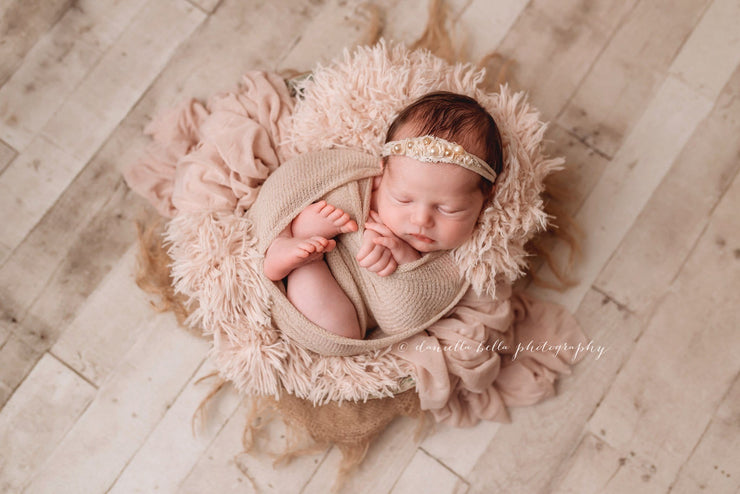newborn baby girl in bowl with soft peach fur fabric