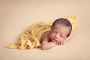 newborn baby with yellow fuzzy swaddling wrap by custom photo props