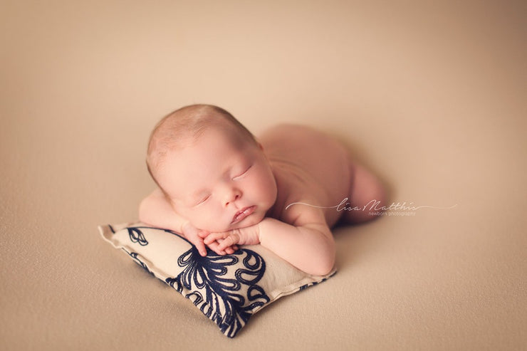 tan and navy blue embroidered newborn posing pillow with baby boy on tan posing cloth by custom photo props
