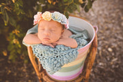 aqua blue  crochet newborn baby blanket with flower design. baby hanging over bucket