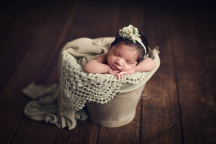 newborn baby girl with light sage green earthy newborn props with baby girl in bucket by custom photo props